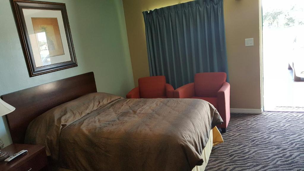 a hotel room with a bed and two chairs at Immokalee Inn in Immokalee