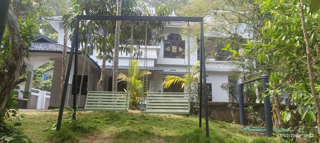 a white house with a swing in front of it at Blue mount stay in Gūdalūr