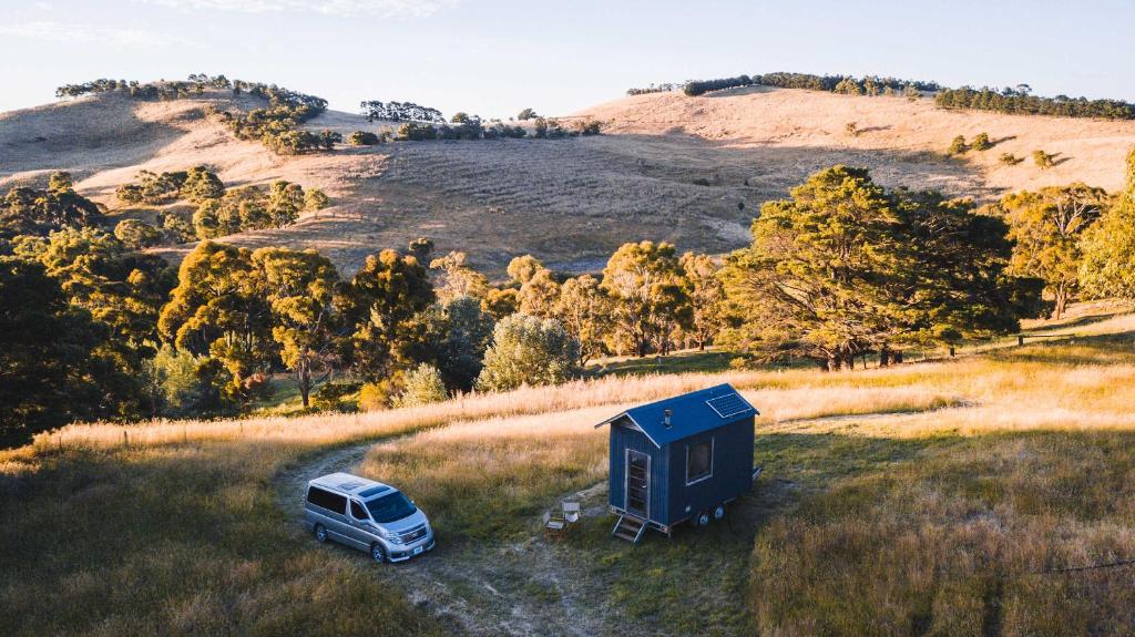 a van parked in a field next to a tiny house at Deep Creek Sunset by Tiny Away in Romsey