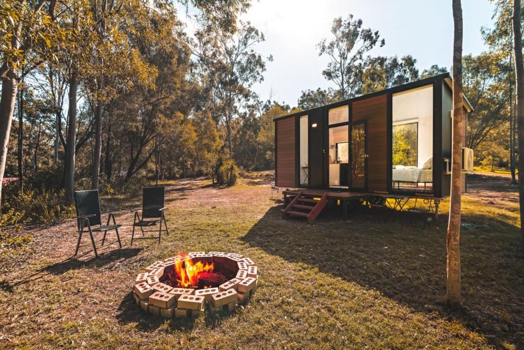 a tiny house with a fire pit in the yard at Mirror Reflections by Tiny Away in Tamborine