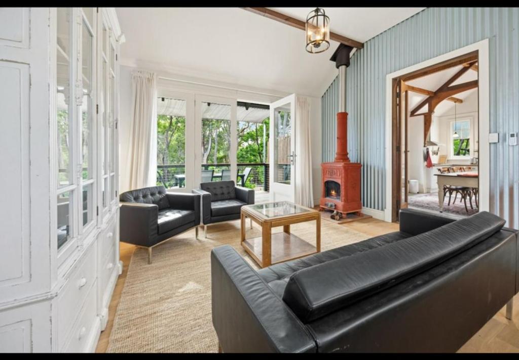 a living room with a black couch and a fireplace at Amara Creek Retreat in Margaret River Town