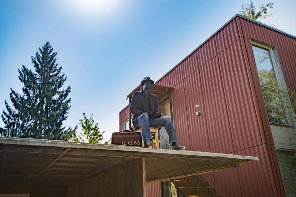 un hombre sentado en el techo de un edificio rojo en Il Cubo en Berna
