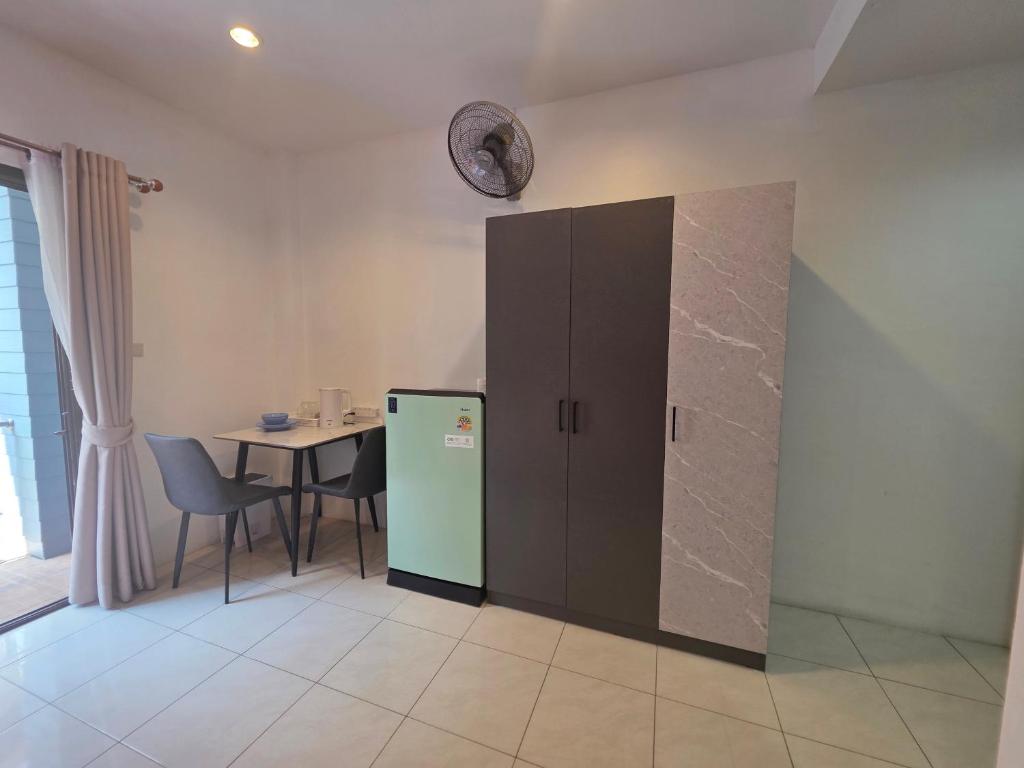a room with a refrigerator and a table with a clock on the wall at Chokdee rooms kata in Kata Beach