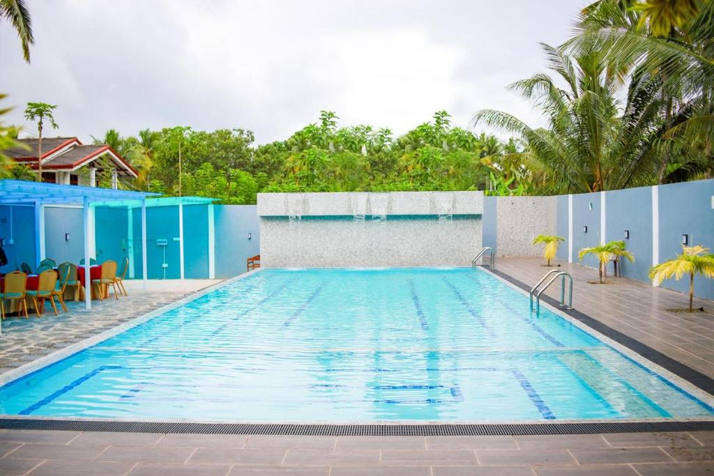 a large swimming pool with tables and chairs at Hotel Friendstar in Minuwangoda