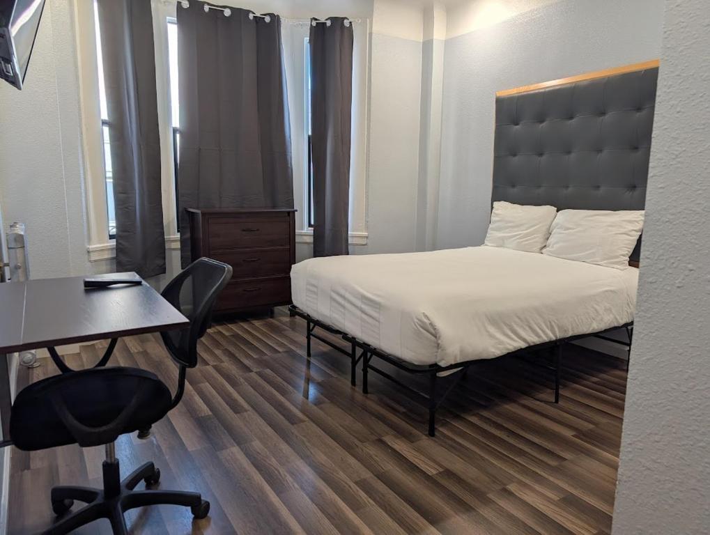 a bedroom with a bed and a desk and a chair at Winsor Hotel in San Francisco