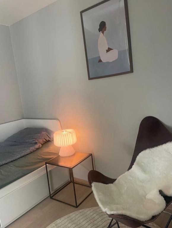 a bedroom with a bed and a chair and a lamp at Cozy private room centrally in Jessheim in Jessheim