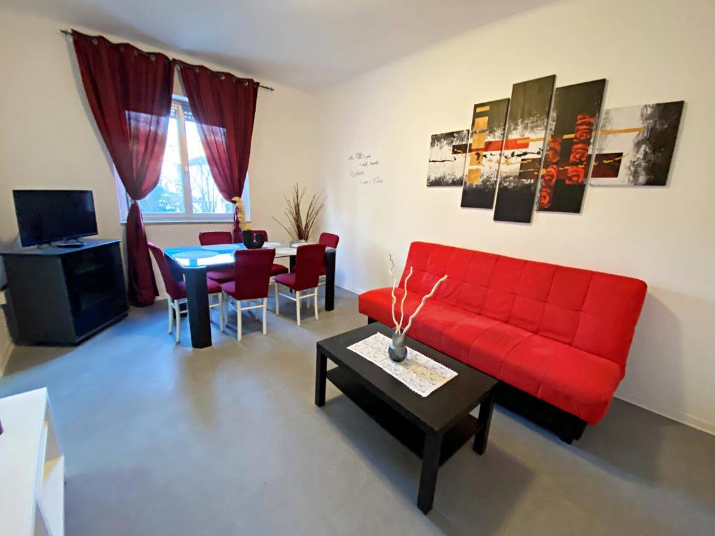 a living room with a red couch and a table at Giulia Home appartamento per 6 persone in Monfalcone