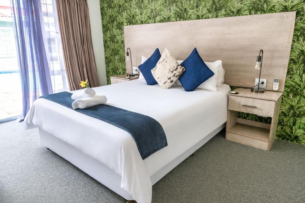 a bedroom with a large white bed with blue pillows at McAllisters on 8th in Durban