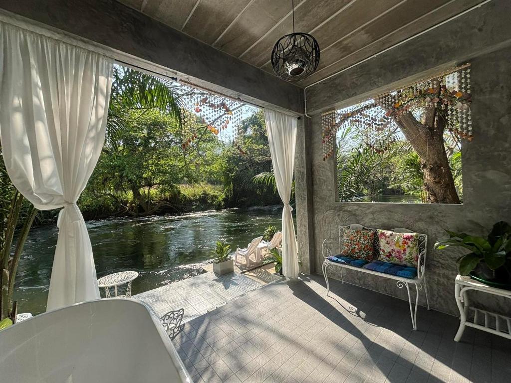 a screened in porch with a view of a river at Baan LungYod Resort in Phetchaburi