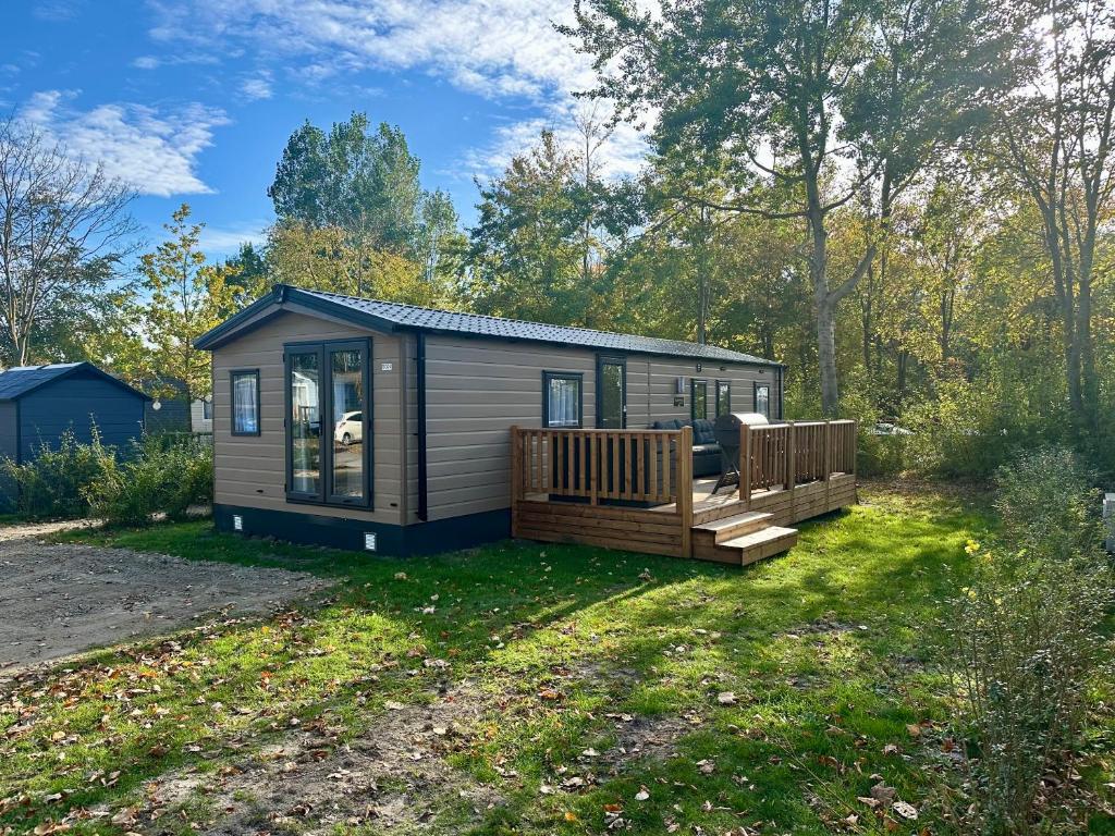 a tiny house with a porch and a deck at Chalet Jersey in Lauwersoog