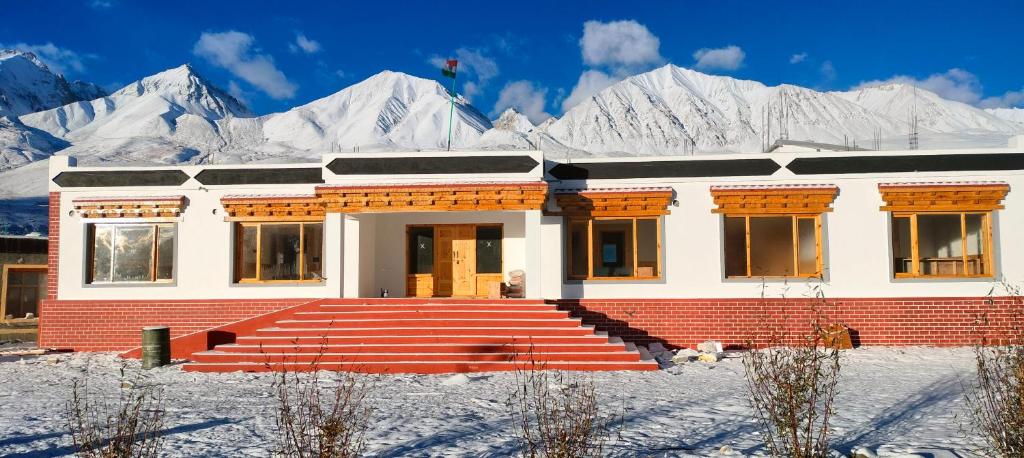 a house with snow covered mountains in the background at Vajra Inn Pangong in Meruk
