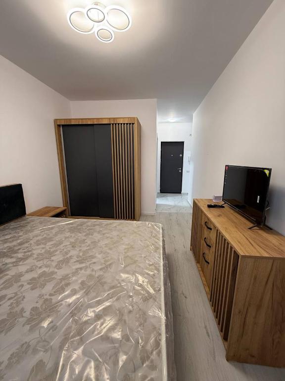 a bedroom with a bed and a flat screen tv at Garsonieră in Chiajna