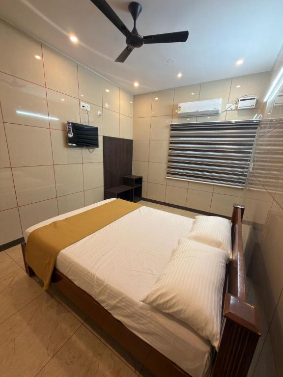 a bedroom with a bed with a ceiling fan at ARS INN AND MINI HALL Vellore in Vellore
