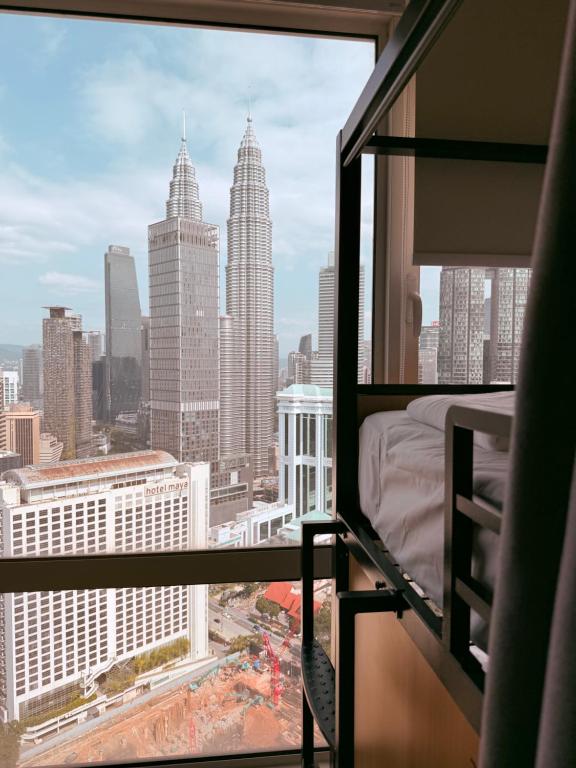 a bedroom with a view of the city from a window at Poshpack Skyline Hostel in Kuala Lumpur