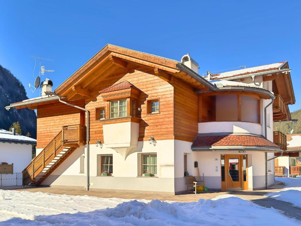a building with a staircase on it in the snow at Cesa Dolomia Apartments in Canazei