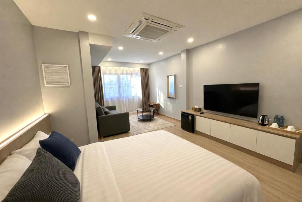 a hotel room with a bed and a flat screen tv at Whiteinn - ไวท์อินน์ in Nonthaburi