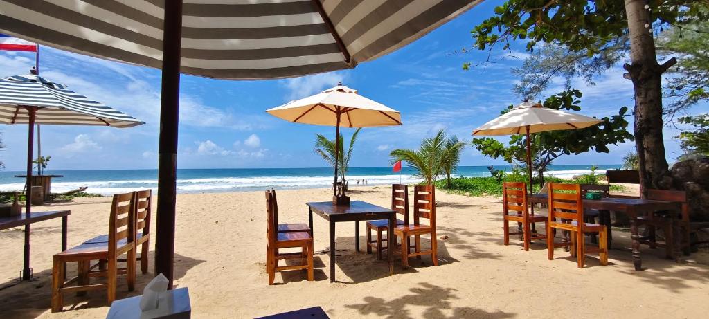 a beach with tables and chairs and the ocean at Unique panoramic sea view pool villas in Phuket