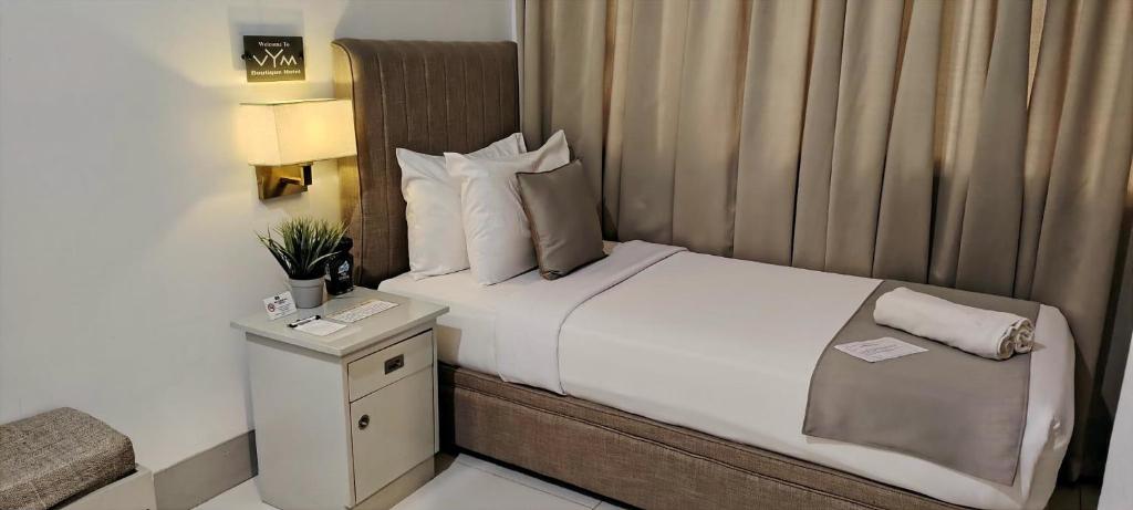 a hotel room with a bed and a night stand at VYM Boutique Hotel in Balulang
