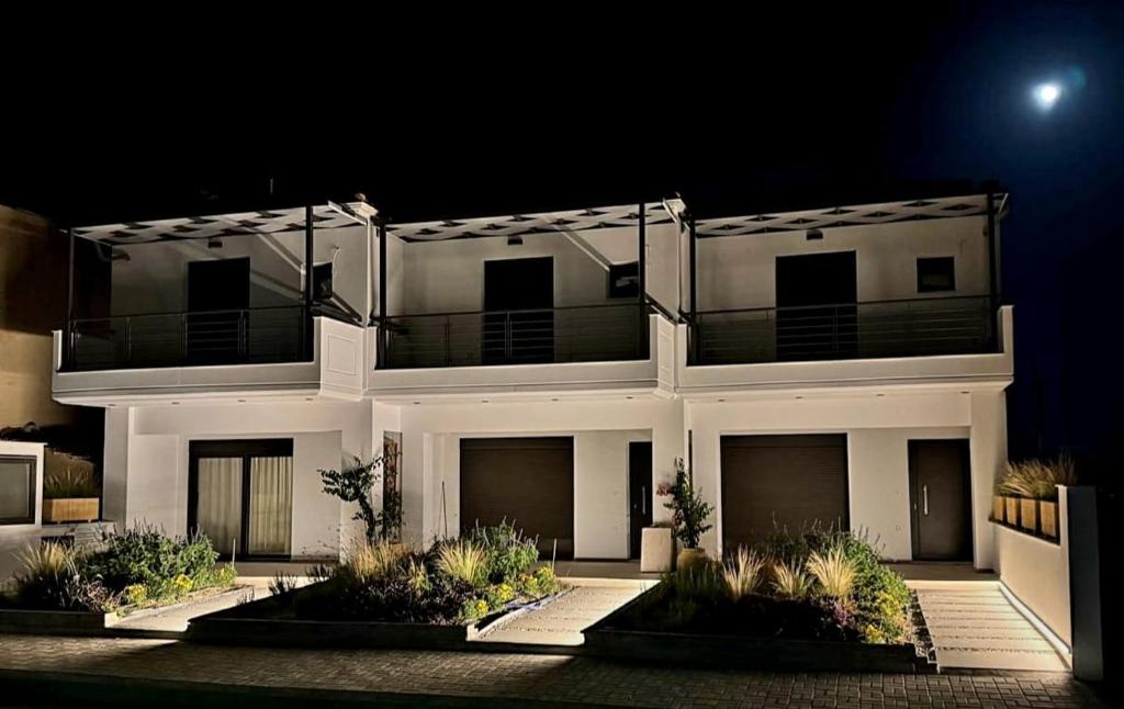 a large white house at night with the moon at Lygonis White Houses in Mitika