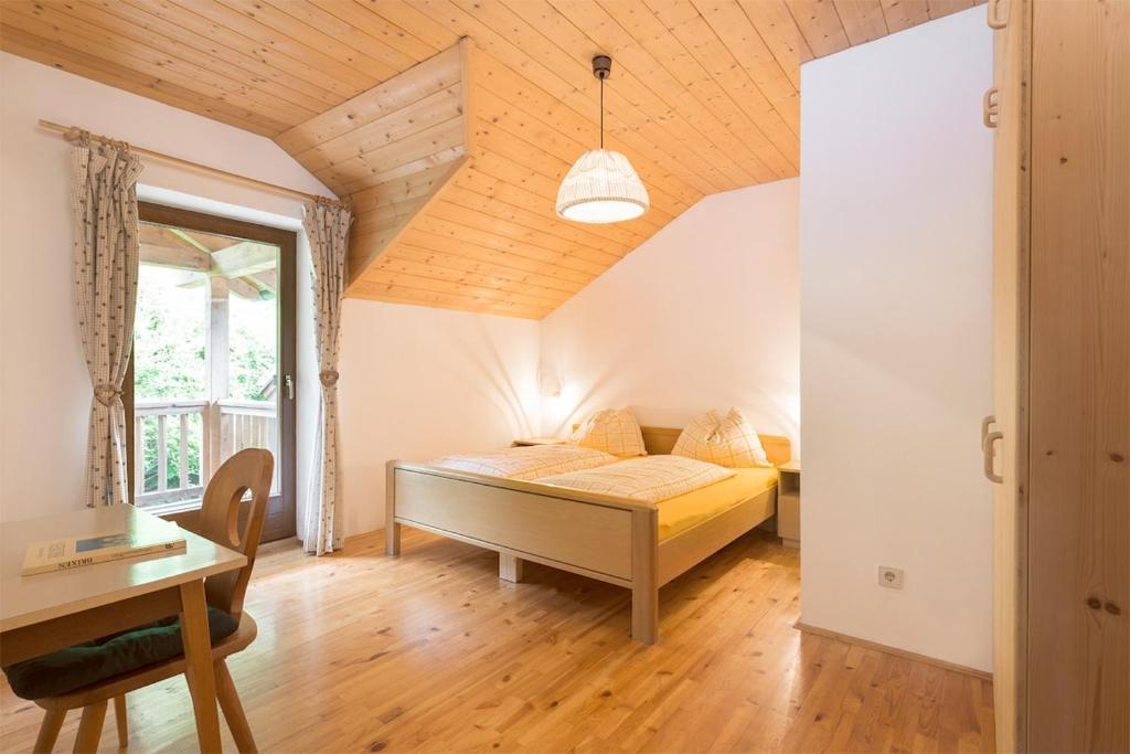 a bedroom with a bed and a desk and a window at Brunelle, Obertörgglerhof in Brixen