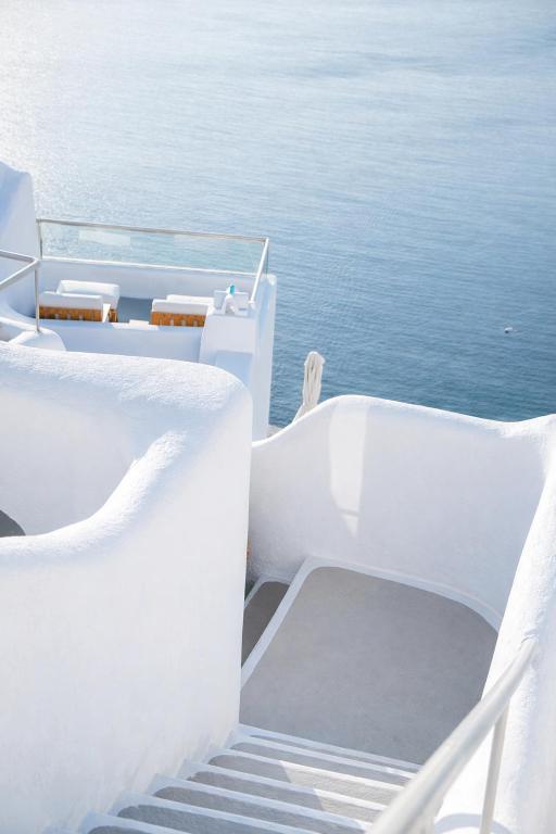 a set of white stairs leading down to the ocean at Ikastikies Suites in Firostefani