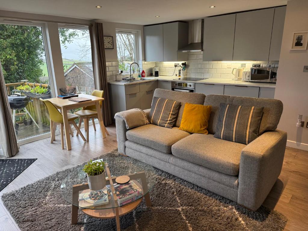 a living room with a couch and a kitchen at The Hutch Devon in Longdown