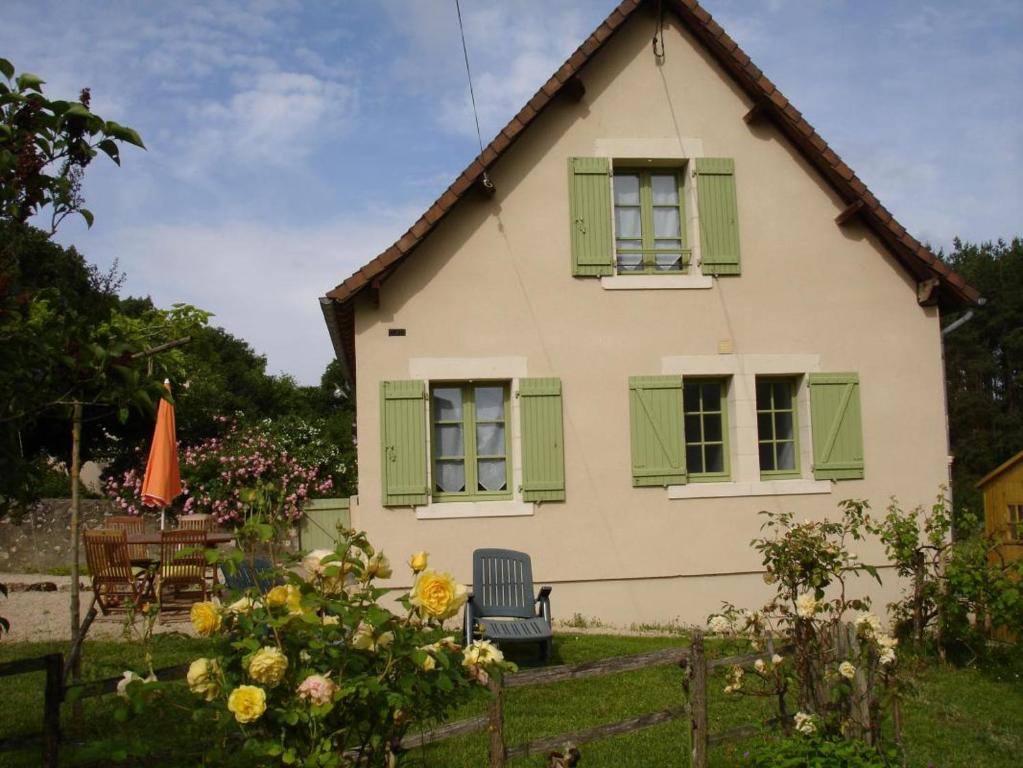 a house with green shuttered windows and a chair at Côté gartempe in Les Hermitières