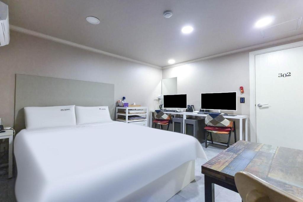 a bedroom with a large white bed and a desk at Prince Motel in Busan