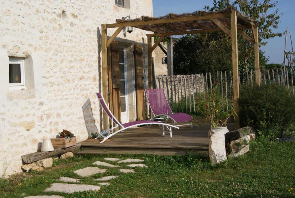 two chairs sitting on a wooden deck next to a building at Le gîte de la roche in Antigny