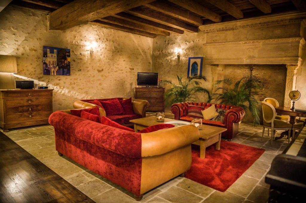 a living room with red couches and a tv at Le clos mélior in Lusignan