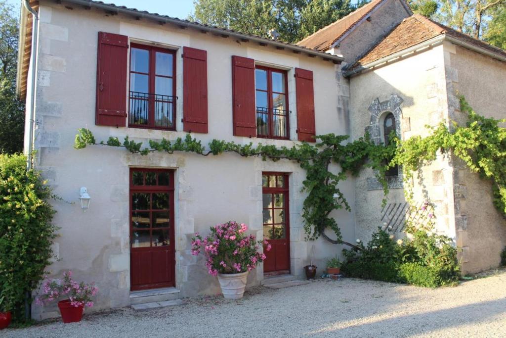 a white house with red shutters and flowers at Les saules in Persac
