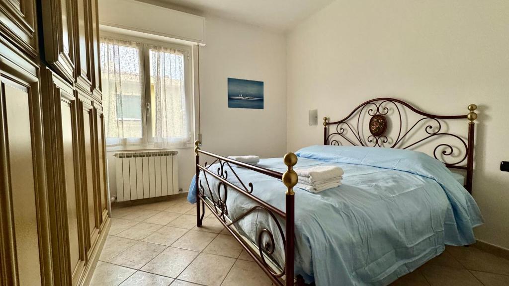 a bedroom with a bed with blue sheets and a window at Garage Privato Elegante Bilocale in Alassio