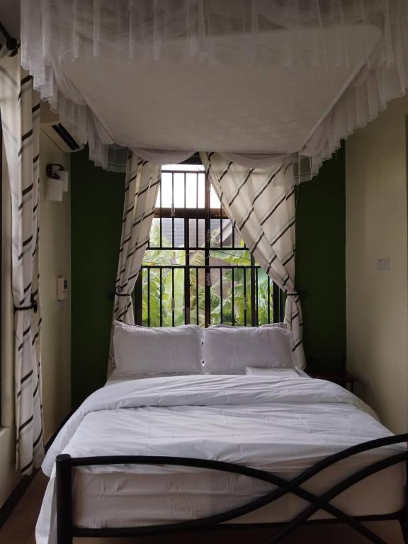 a bed in a room with a window and a bed with white sheets at Greenhome apartment in Poli