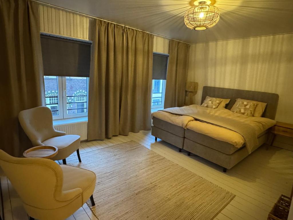 a bedroom with a bed and a chair and windows at vakantie appartement D'vine in Valkenburg
