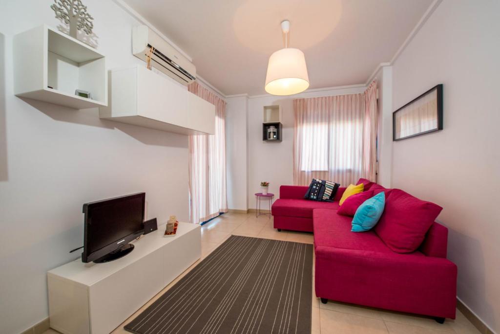 a living room with a red couch and a tv at Alicante Apartments in Alicante