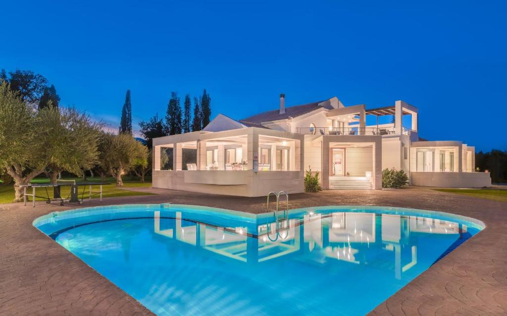 a large house with a swimming pool in front of it at Astarte Villas - Istar Villa with Tennis Court in Makhairádhon