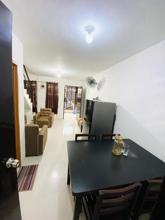 a dining room and living room with a black table and chairs at Sparrow Transient Townhouse in Davao City
