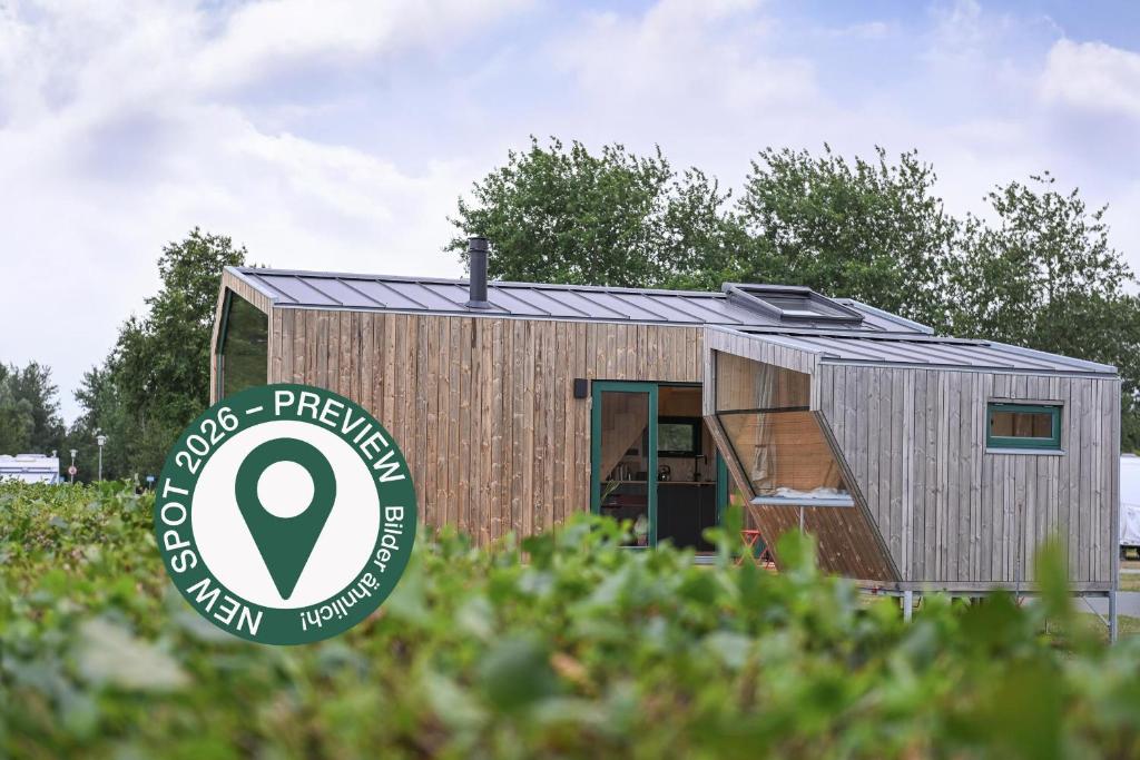 a tiny house with a sign in a field at Tiny House Connect 7 - Green Tiny Spot Schillig in Wangerland