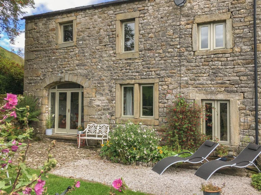 a stone house with two chairs in front of it at Litton Hall Barn Cottage in Skipton