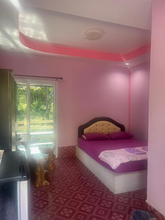 a pink bedroom with a bed and a window at Martin, Local Guide & Camping in Ban Phang Kan Nua