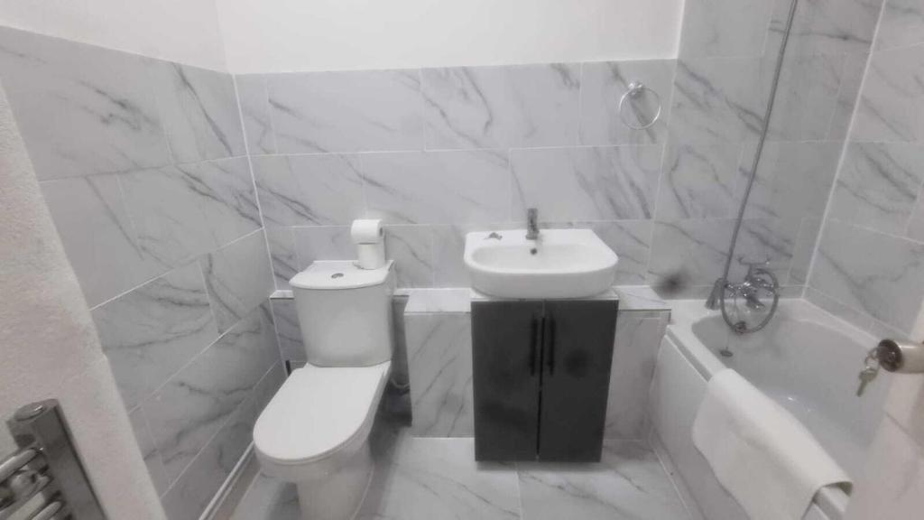 a white bathroom with a toilet and a sink at Extra Large One Bedroom Flat with Parking in London