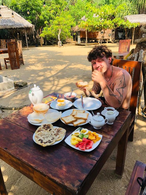 a man sitting at a table with plates of food at Echo retreat in Tangalle