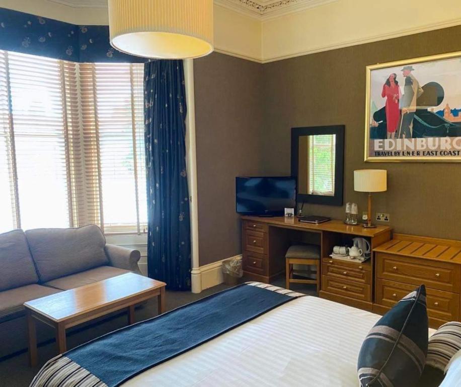 a bedroom with a bed and a couch and a television at The Dutch Mill Hotel in Aberdeen