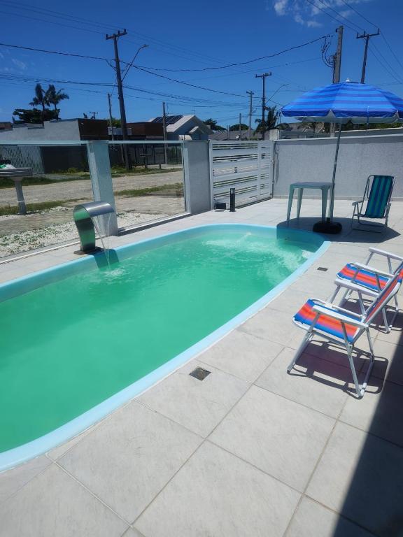 a swimming pool with two chairs and an umbrella at Casa espaçosa com piscina, a 2 quadras do mar! in Guaratuba