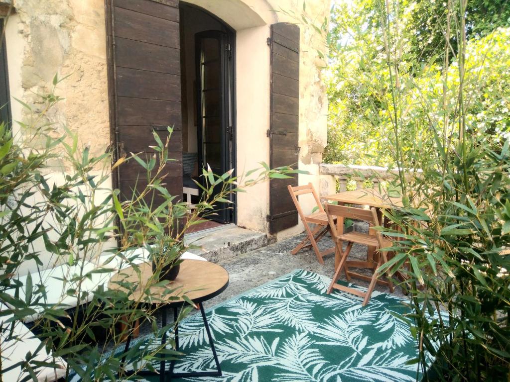 a patio with a wooden table and chairs and a table and chairs at Les feuillets de la Buire in Monteux