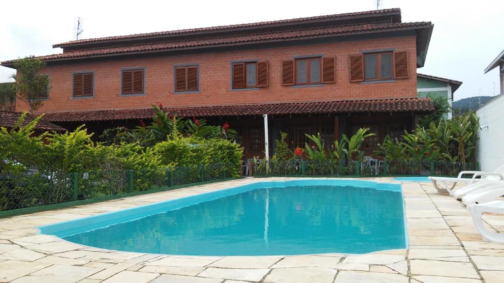 a house with a swimming pool in front of a house at Sol e Cia casa de temporada in Caraguatatuba