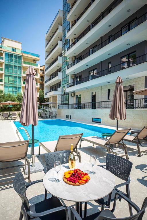 a table with a plate of fruit on it next to a pool at Adriatic Residence in Budva