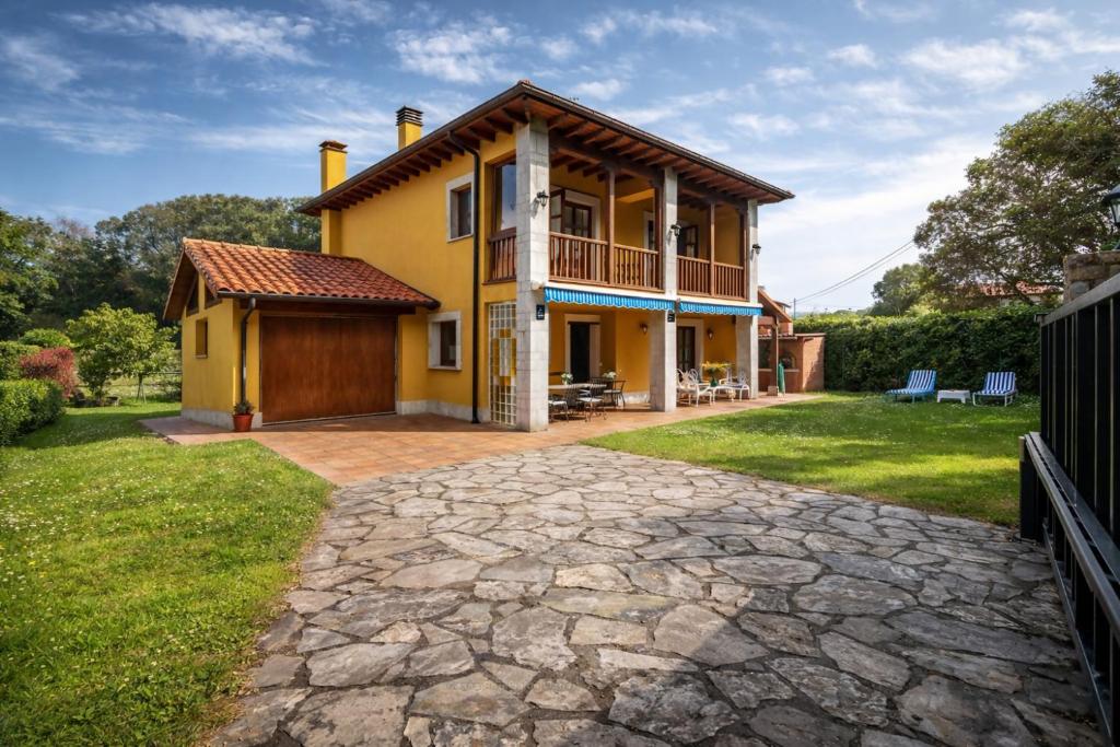 a large yellow house with a stone driveway at Casa cerca Playa Cuevas del Mar Llanes - River in Llanes