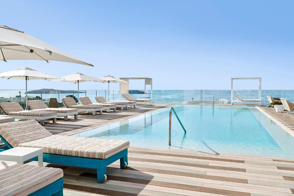 a swimming pool with chairs and umbrellas on a building at Iberostar Selection Santa Eulalia Adults-Only Ibiza in Santa Eularia des Riu