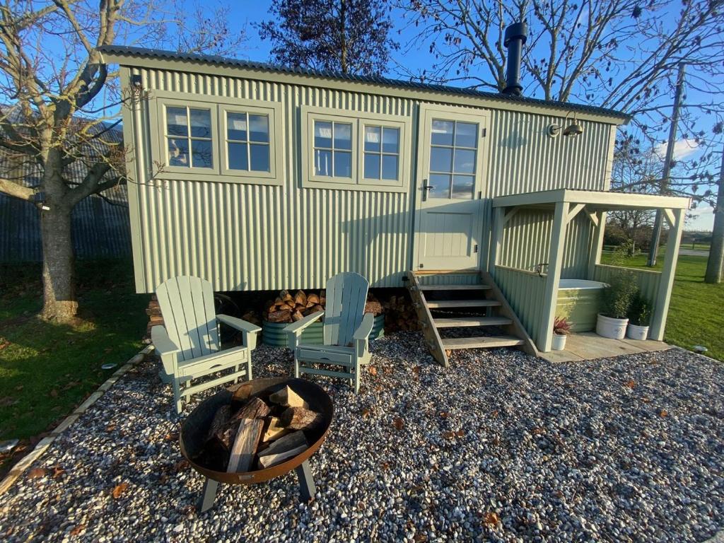 a tiny house with two chairs and a fire pit at Happy Place Shepherds Hut in Bishops Tachbrook